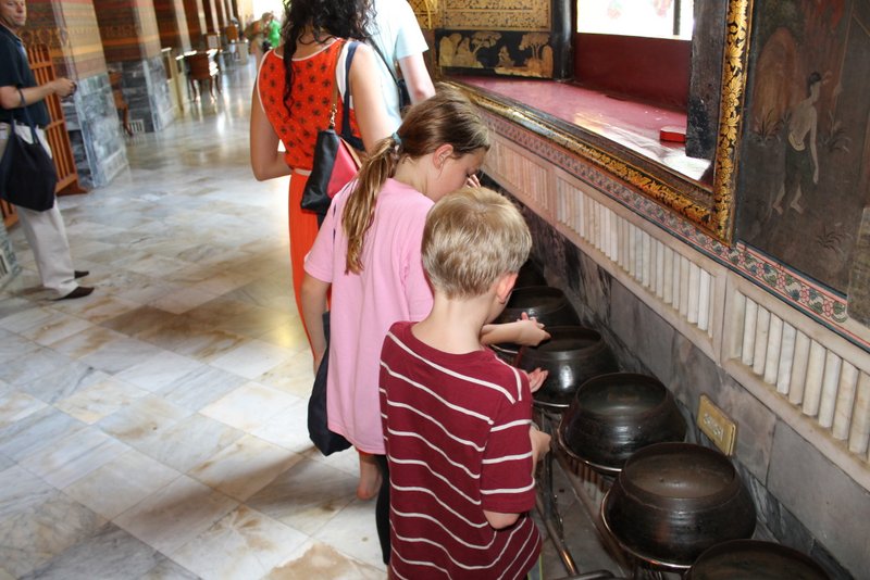 The kids putting money into the many offering bowls